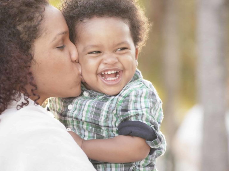 A woman holding and kissing a child