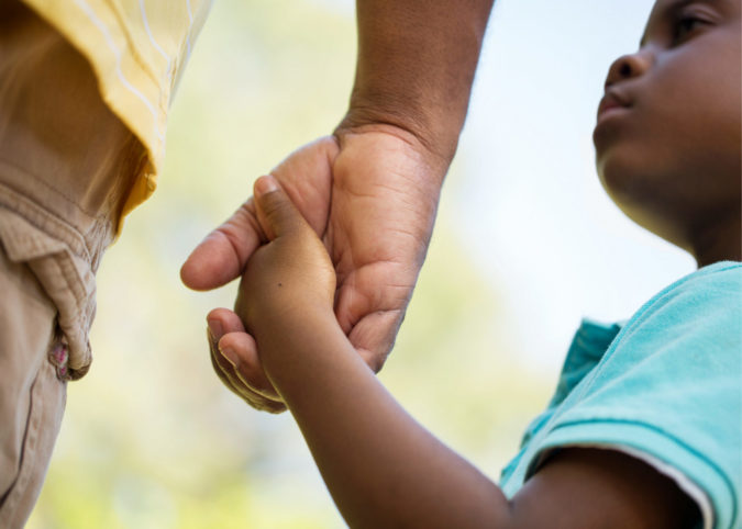 close up shot of a young child holing an adult's hand