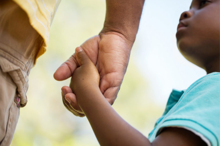 close up shot of a young child holing an adult's hand