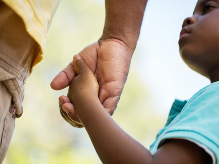 close up shot of a young child holing an adult's hand