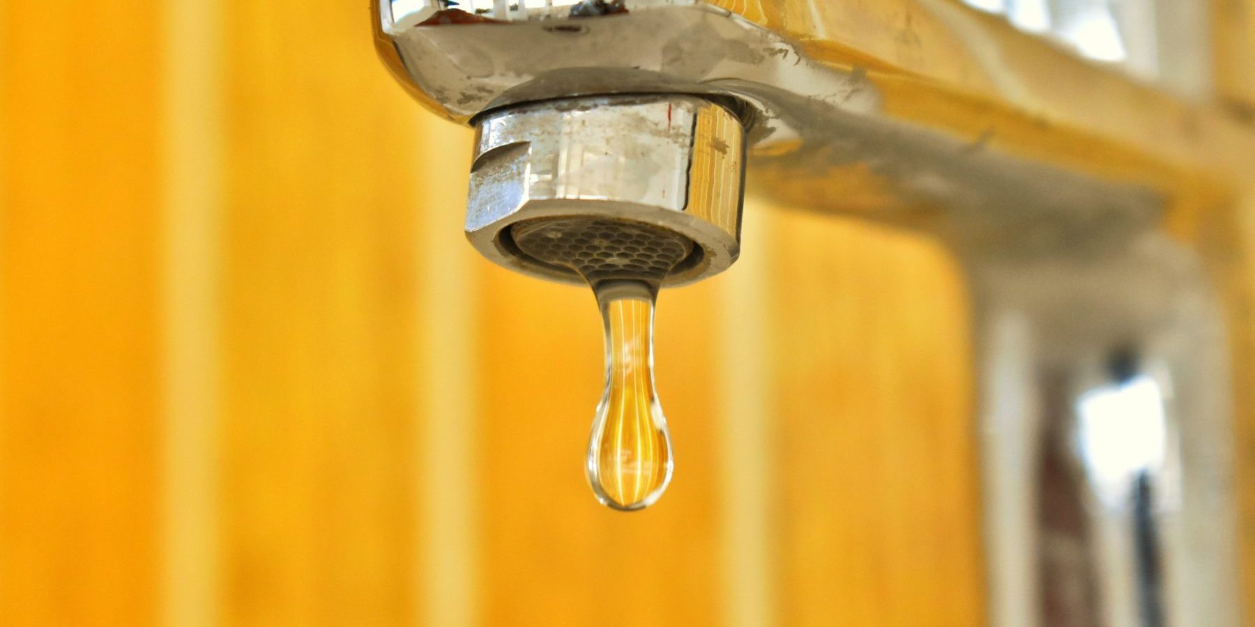 pexels-nithin-pa-2583028 Close up of water dripping out of a faucet with a yellow background
