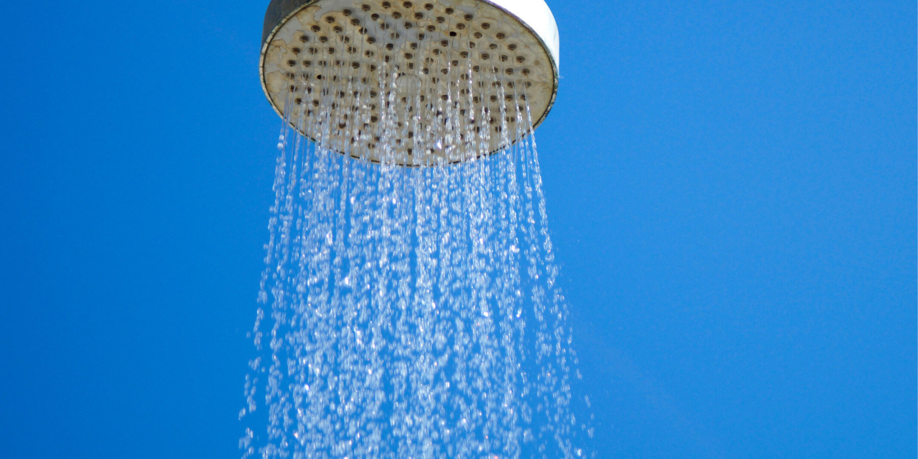 shower head sprinkling water in front of a blue background