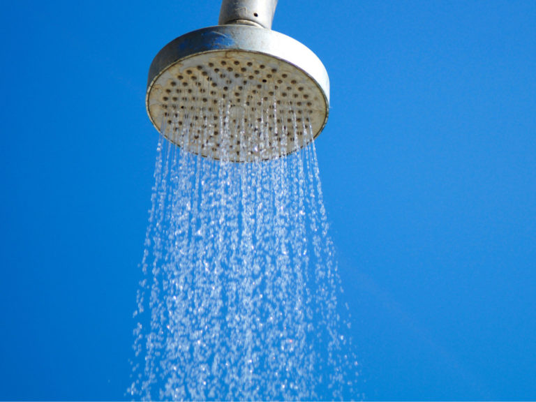 shower head sprinkling water in front of a blue background