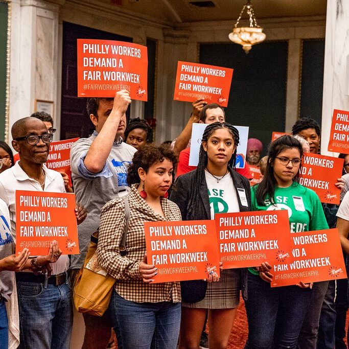 Organizers hold "Philly workers demand a fair workweek" signs in City Council.