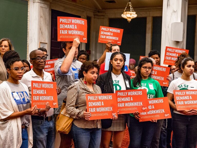 Organizers hold "Philly workers demand a fair workweek" signs in City Council.